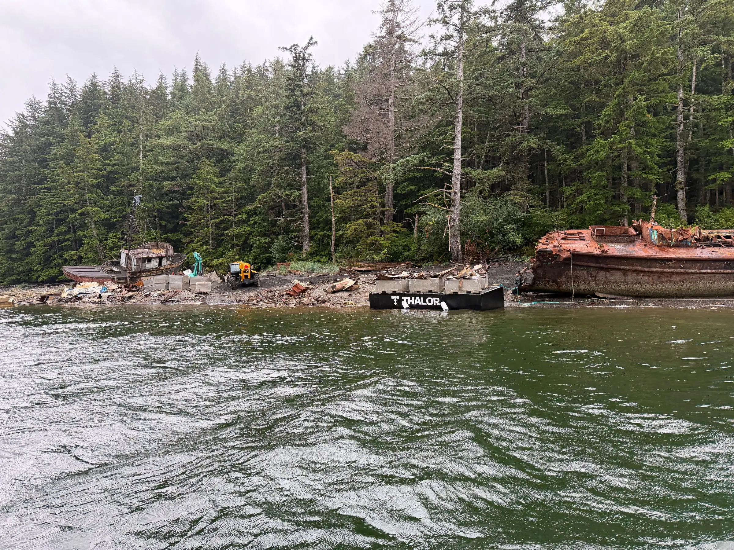 Ode beached beside a rusting hull as debris is loaded for removal